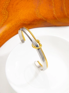 Macro detail of two-tone gold and silver knotted stainless steel adjustable bangle