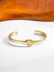 Close-up of dual-tone PVD 18k gold knot detail on a sleek stainless steel bangle