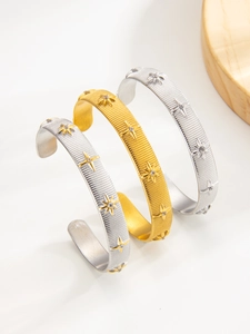 Detailed view of brushed PVD gold and silver C-cuff bangles with octagonal star embossing