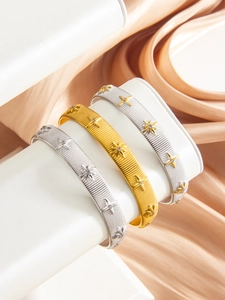 Detailed macro view of brushed PVD 18k gold and silver bangles with starburst patterns
