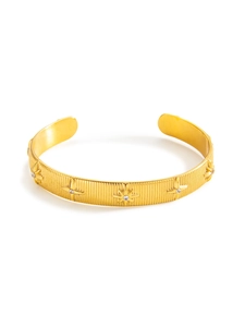 Macro detail of gold-plated cuff bracelet with star patterns and inlaid zircons