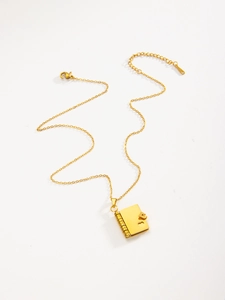 Detail of a vintage gold book pendant featuring a heart cutout and clasp on a chain