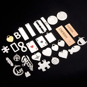 Variety of stainless steel and wooden pendants in heart, puzzle and logo shapes on black