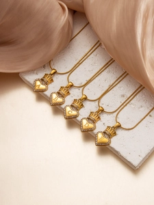Macro detail of gold crown heart pendants with A-E letters on textured stone