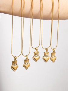 Detailed macro of gold heart letter pendants with crown accents and sparkling crystals