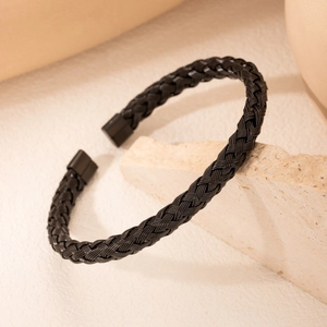 Minimalist black woven titanium steel bracelet with a sleek magnetic clasp on a stone base