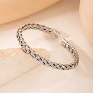 Polished silver braided open cuff bracelet in stainless steel on beige stone base