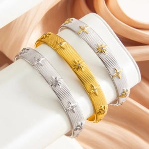 Three-piece PVD 18k gold and silver stainless steel star bangles on silk backdrop
