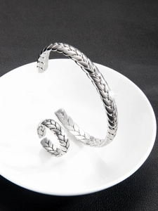 Detalle del conjunto de brazalete y anillo de plata con tejido de espiga en bandeja de porcelana