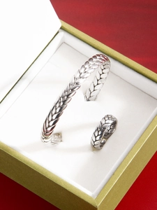 Detalle del conjunto de brazalete y anillo de espiga plateado con textura tejida
