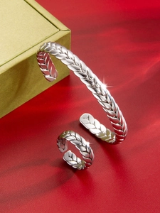 Detalle de brazalete y anillo de plata con grabado de espiga sobre cuero rojo suave