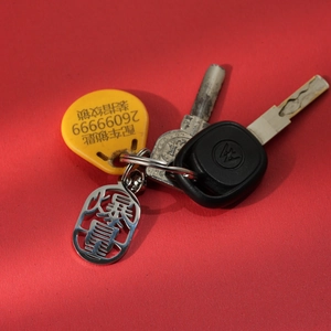 Close-up of silver stainless steel keychain with Chinese characters for wealth on red background