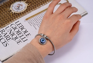 Macro shot of silver snake chain bracelet with sparkling blue evil eye charm inlay