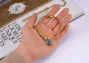 Detail of 18K gold snake chain bracelet with crystal-studded Evil Eye charm