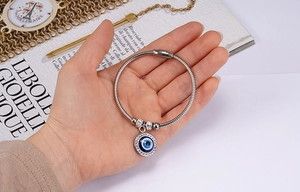 Macro detail of silver snake chain bracelet with blue evil eye charm and rhinestones