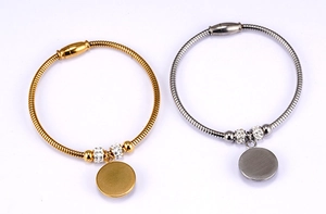 Detail of 18K gold and silver snake bone bracelets with evil eye charms and rhinestones