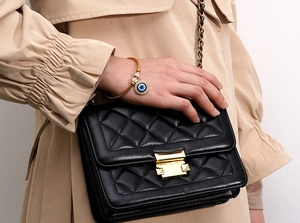 Detail of 18K gold plated snake chain bracelet with evil eye charm on female wrist