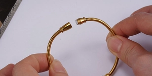 Close-up of 18K gold magnetic clasp on snake chain bracelet showing snapping mechanism
