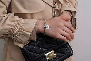 Close-up of a silver Tree of Life charm bracelet with snake chain worn on a wrist