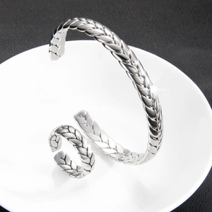 Conjunto de pulsera y anillo abiertos plateados con diseño trenzado en plato blanco