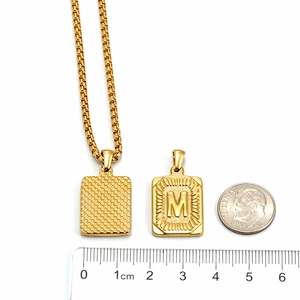 Detailed size comparison of gold M initial pendant with ruler and coin reference