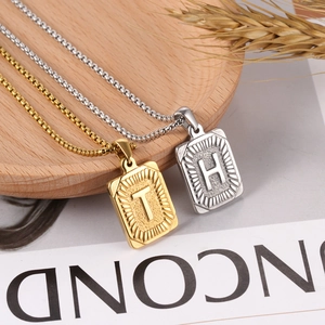 Close-up of gold and silver rectangle letter T and H pendants with square pearl chains