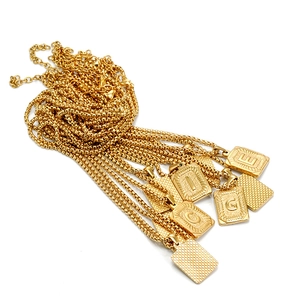 Macro view of gold-plated stainless steel letter pendants with box chain detailing