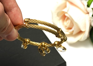 Detailed shot of golden wire bracelet featuring Hamsa charm and sparkling rhinestone pendant