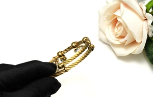 Detailed view of golden wire rope bracelet with Fatima hand charm and blue stones