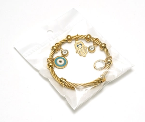 Detailed view of golden twisted cable bracelet with Hamsa and Evil Eye charms