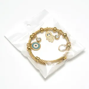 Gold braided wire bangle with Hamsa Hand and Evil Eye charms on white background
