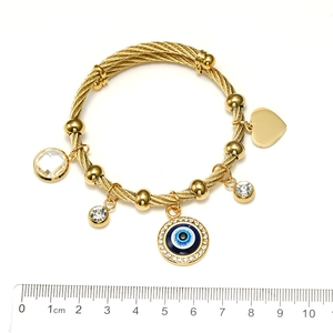 Detail of gold evil eye cable bracelet with heart and crystal charms on white background