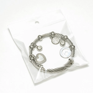 Gros plan sur un bracelet câble torsadé argenté avec breloques cœur et étoiles