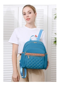 Detail of blue Oxford backpack with diamond quilting and rivets on a female model