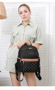 Detail of black oxford backpack featuring gold rivets and woven trim for travel
