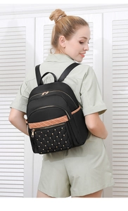 Close-up of black oxford backpack showing gold rivets and quilted pocket details