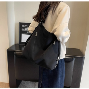 Detail view of the black canvas bag with dual metal zipper pockets and nylon texture