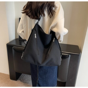 Detailed back view of a black large capacity canvas tote bag worn by a model in interior