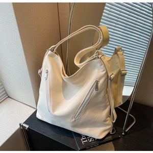Detailed close-up of beige canvas bag showing silver zippers and textured fabric