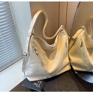 Detail of off-white canvas hobo bag showing vertical zippers and adjustable strap