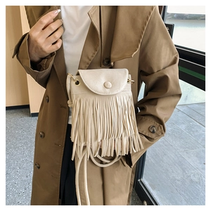 Détail d'un petit sac à bandoulière beige à franges avec anneau métallique doré élégant