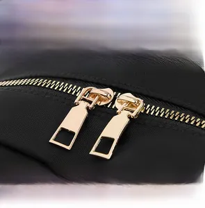 Detailed close-up of premium gold metal dual zippers on black Oxford fabric backpack
