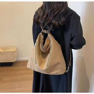 Detail view of khaki canvas backpack featuring parallel zippers and metal hardware ring