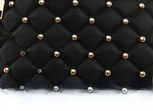 Detail of black quilted oxford fabric backpack with stylish gold bead studs and rhombus pattern