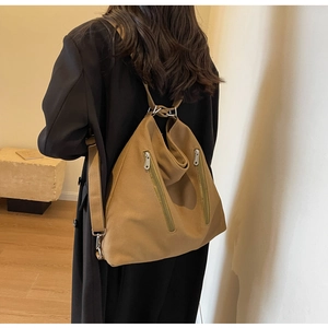 Detail of khaki canvas backpack featuring dual vertical zippers and minimalist triangular design