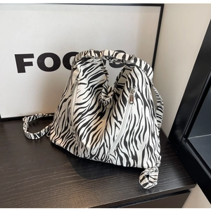 Macro detail of zebra print canvas bag featuring decorative side silver zippers and texture