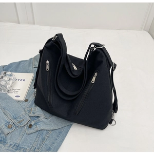 Detail of black canvas tote bag showing vertical zipper pockets and durable thick texture