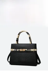 Detail of black leather handbag with snakeskin texture panels and gold turn-lock closure
