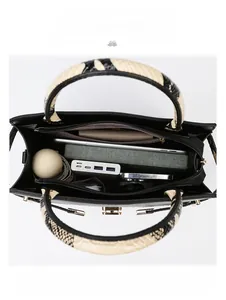 Internal view of black tote bag showing spacious compartments and snake print handle detail