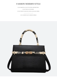 Detail of black textured leather handbag with gold twist lock and rounded handles